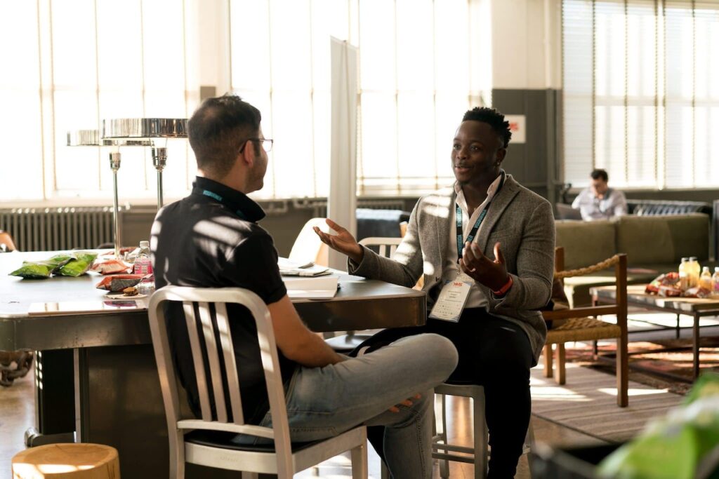 two men sitting at a table talking