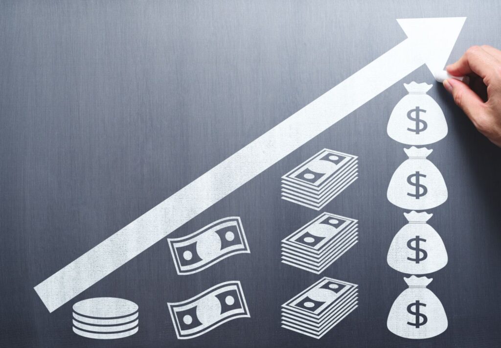 white arrow on blackboard pointing up at 45º angle with money symbols underneath to depict increasing cash flow