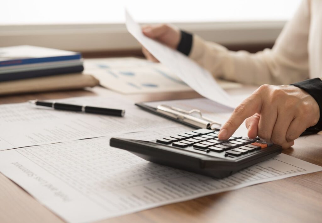 closeup of someone using a calculator on a desk and holding a piece of paper