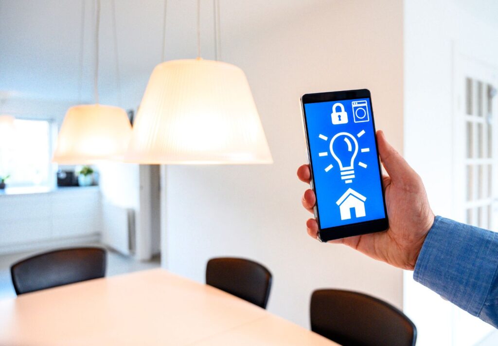 a hand holding a phone with a light bulb and a house on the screen