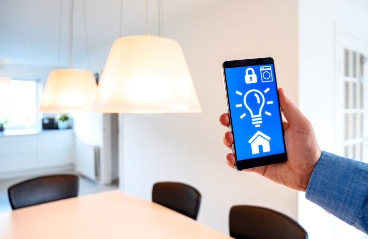 a hand holding a phone with a light bulb and a house on the screen